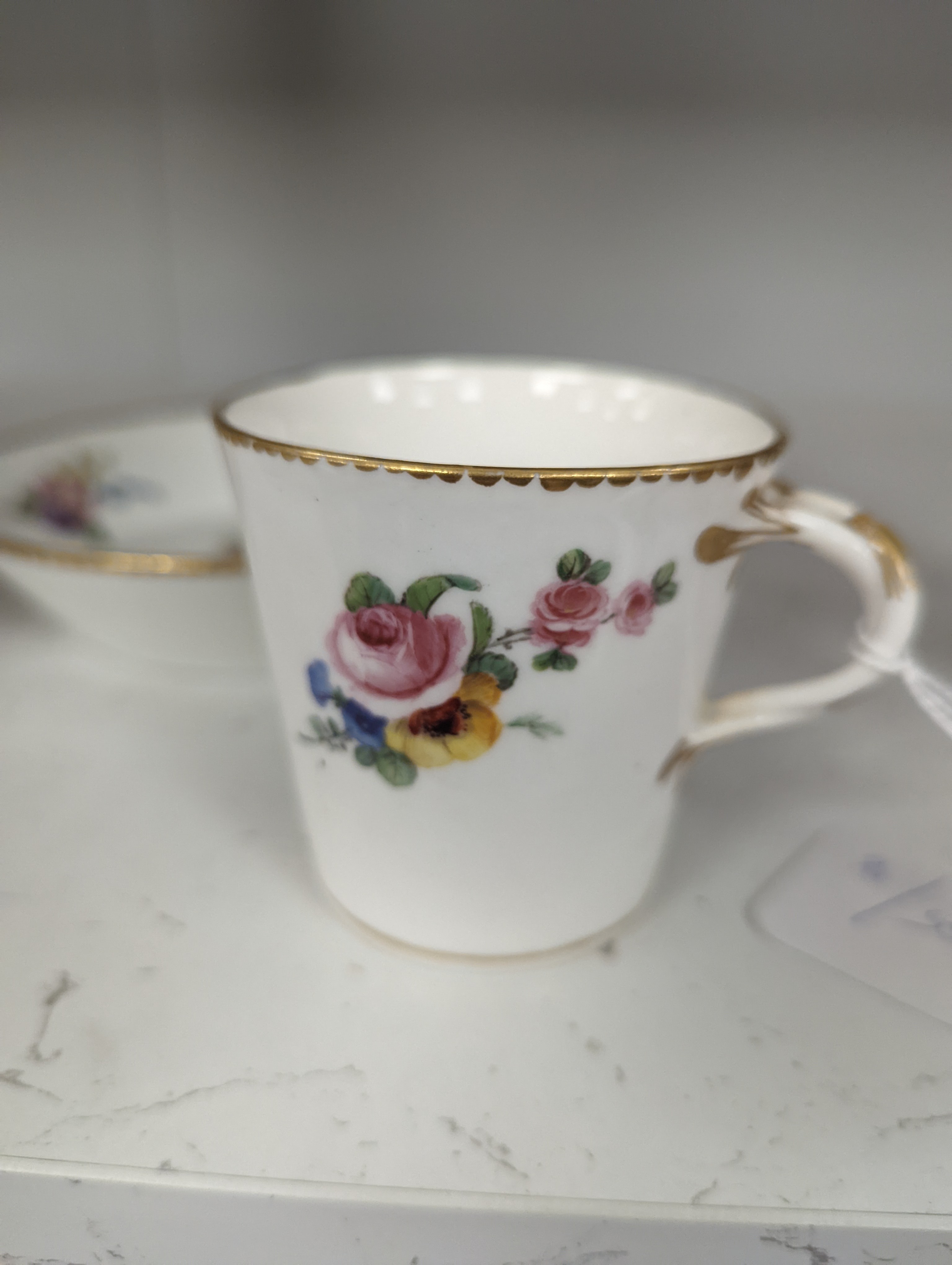 A Sevres tapering cup with entwined handle and cover and stand painted with flowers, date code for 1780, painters mark for Le Bel jnr., square incised marks, height 10.5cm